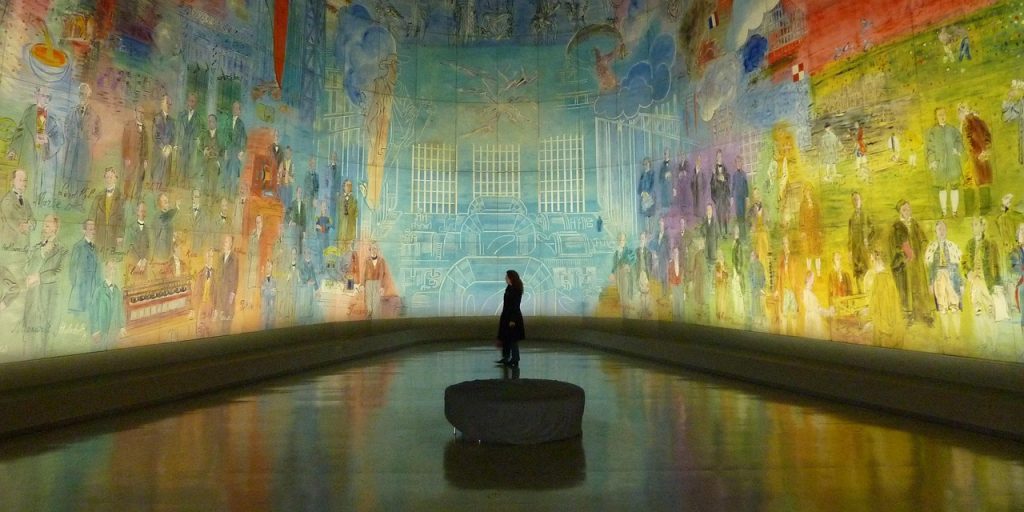 Sortie au musée (nos sorties culturelles). La silhouette d’une personne dans une pièce sombre aux murs peints et lumineux.
