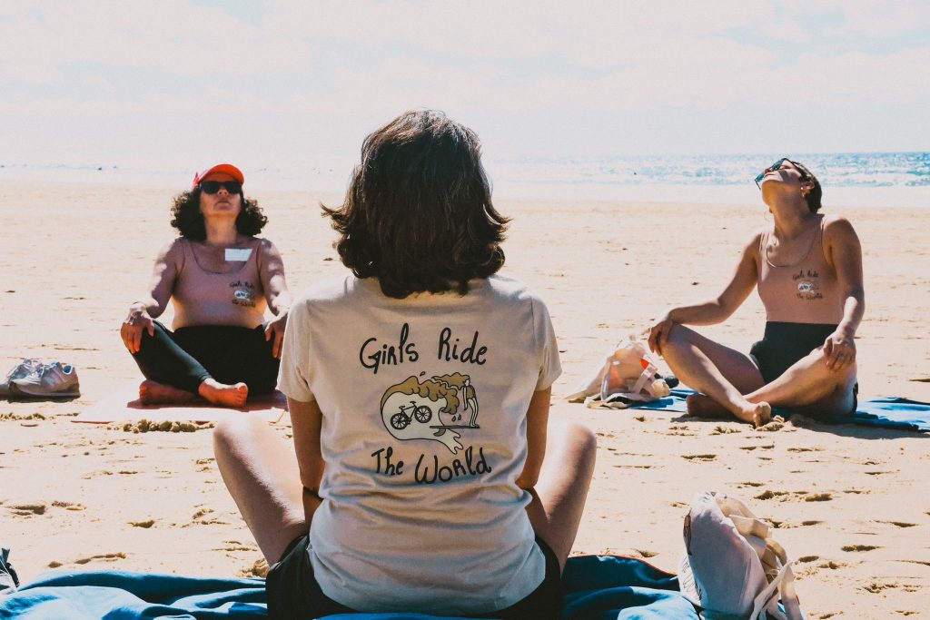 Week-end bien-être avec GIRLS RIDE THE WORLD. Trois femmes assises en tailleur sur la plage.